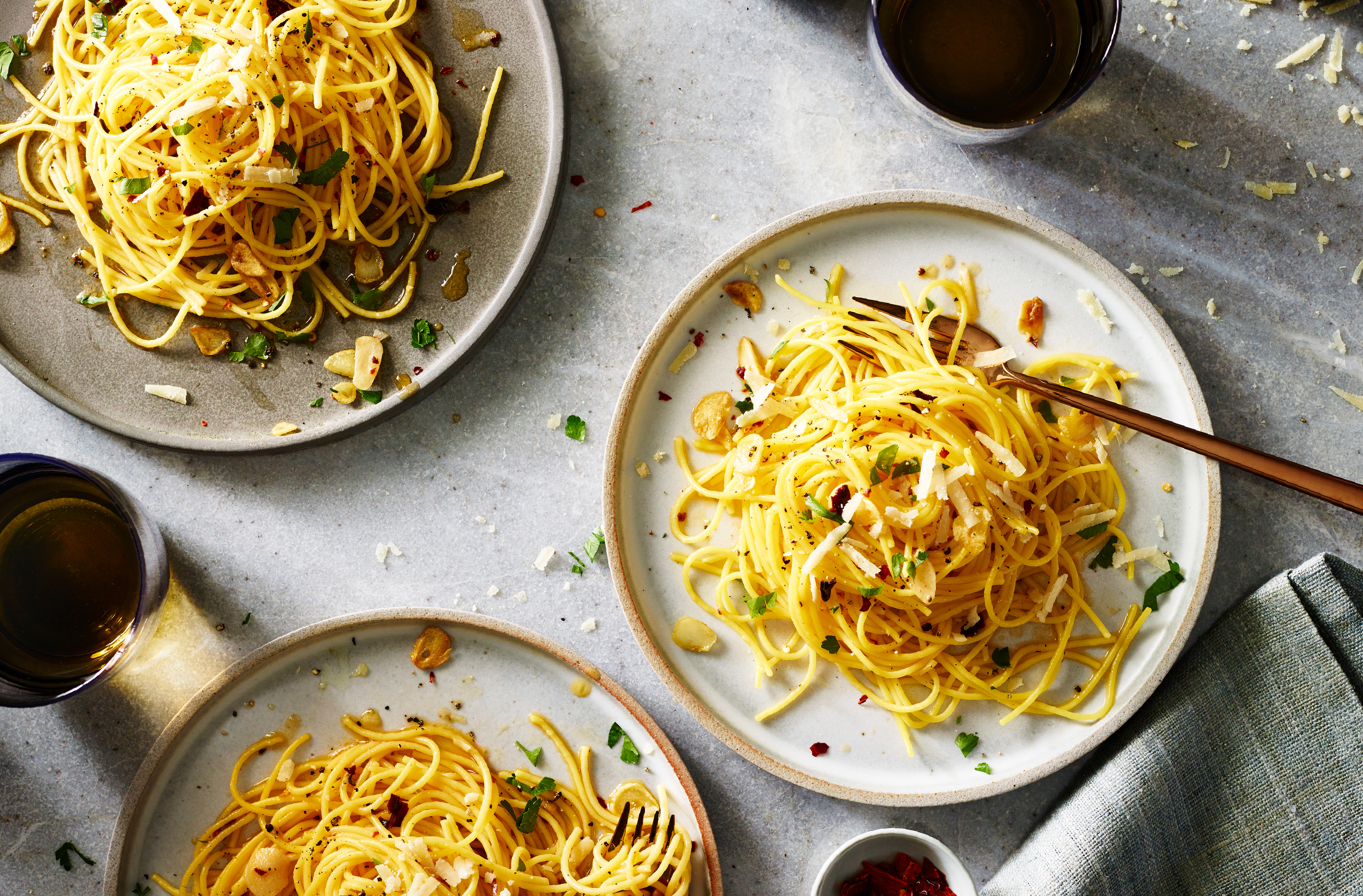 Three plates of spaghetti tossed with garlic oil and cheese
