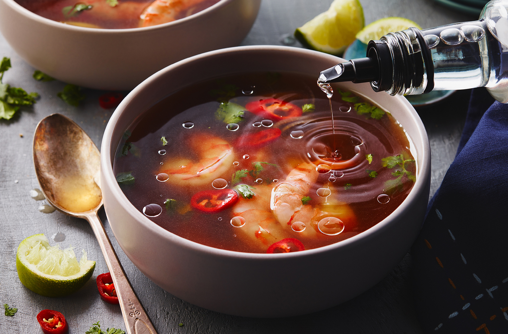 A bowl of Thai tom yum soup with shrimp & slices of hot peppers