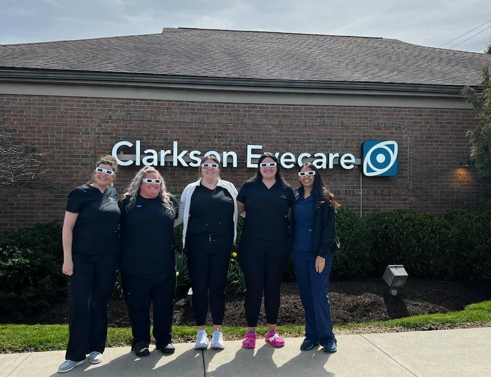 Clarkson Eyecare eye care center in Marysville, OH team of eye care experts standing in front of Clarkson Eyecare outside sign logo smiling group photo 