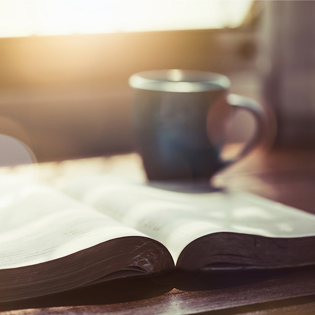 Picture of a cup of coffee and book on a desk.