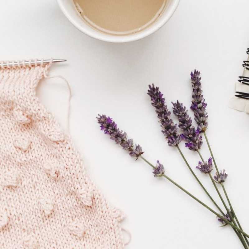Piece of knitting with cup of coffee, sprig of lavender, and a notebook