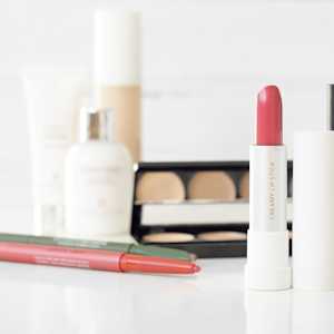 Some makeup in the background with a lipstick in the foreground