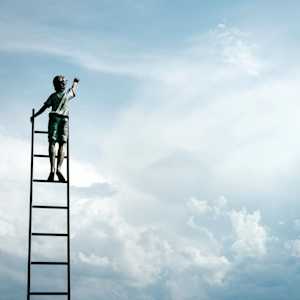 boy standing on ladder reaching for the clouds