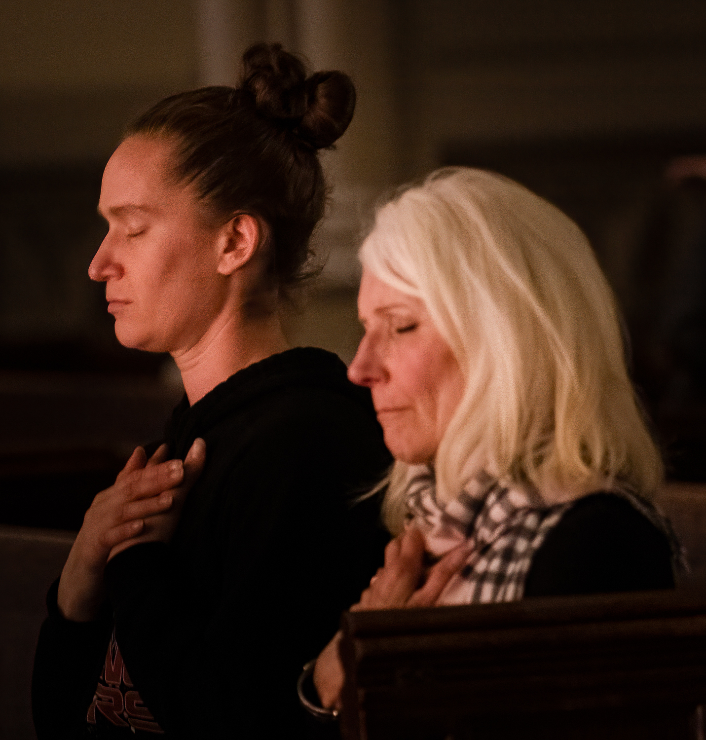 Two women silently praying with eyes closed