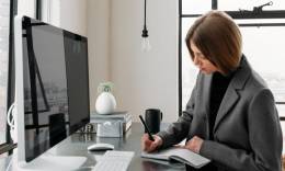 Mujer freelance escribiendo en frente de su ordenador.