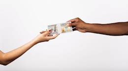 Two hands exchange stack of hundred dollar bills.