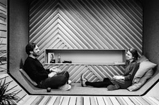 Two people sitting and talking in the wooden lounge area.