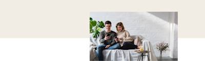 A couple sitting on a couch looking at their phones.