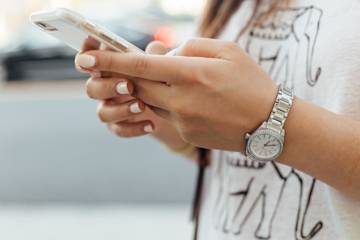 Primo piano delle mani di una donna che controlla il suo smartphone.