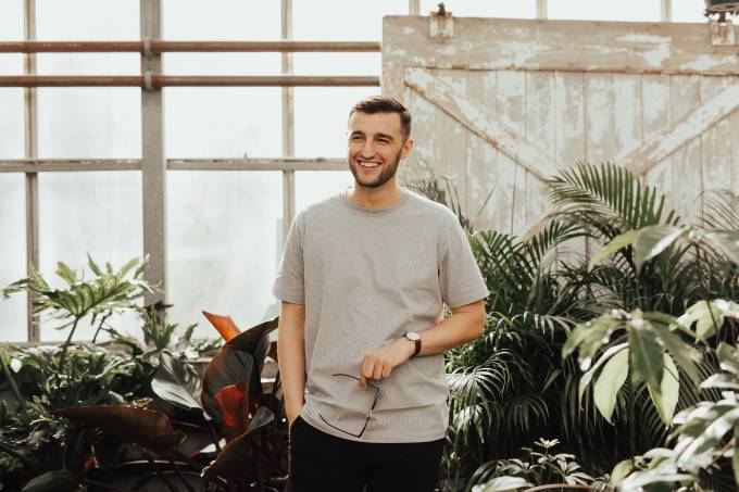 Un homme souriant se tient devant des plantes.