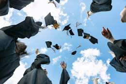 young graduate students throwing their caps to the sky.