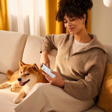 Woman sitting on a sofa looking at the N26 app with her dog.