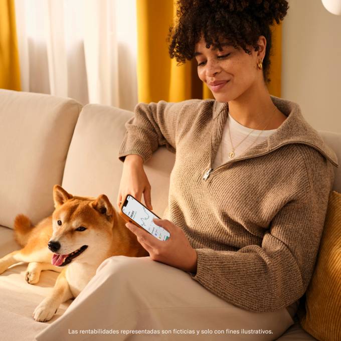 Mujer sentada en un sofa mirando la aplicación de N26 junto a su perro.