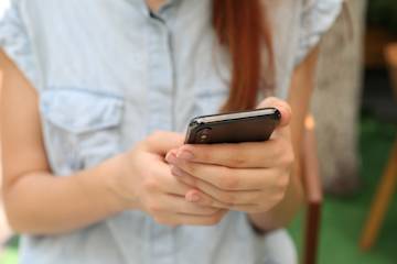 Close up of the hands of a girl checking her phone.
