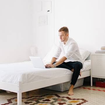 Man working on his bed with a laptop.