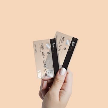 An elevated hand holding two N26 Visa cards against a beige background.