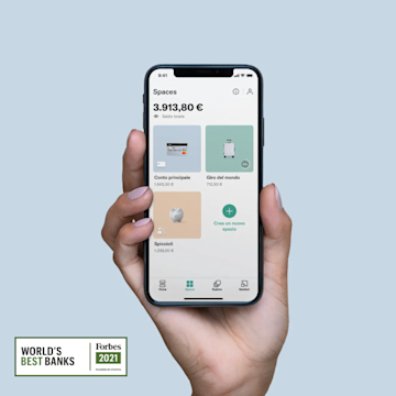 Una mano che tiene in mano un iPhone X con la schermata Spaces aperta sull'app N26 con il miglior logo della banca di Forbes.
