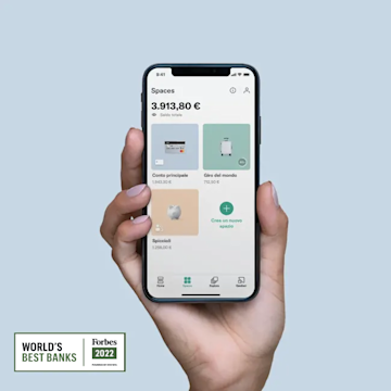 Una mano che tiene in mano un iPhone X con la schermata Spaces aperta sull'app N26 con il miglior logo della banca di Forbes.