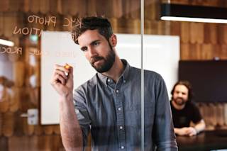 An N26 employee writing onto a meeting room’s glass wall with a marker.