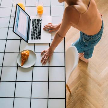 Woman with laptop and croissant.