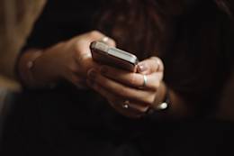 Woman wearing a black dress and using her mobile.