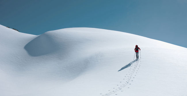 Travel Insurance Header image with a snow mountain and a guy walking on it.