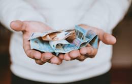 Manos sujetando billetes de euros en posición de ofrecimiento.