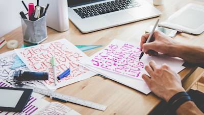 Ein Freelancer, der von Hand kalligrafische Buchstaben malt.