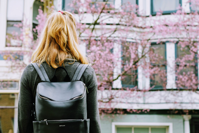 woman wearing backpack facing concrete building. Photo Credit to Tim Gouw.