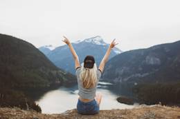 Woman on top of mountain with arms open.