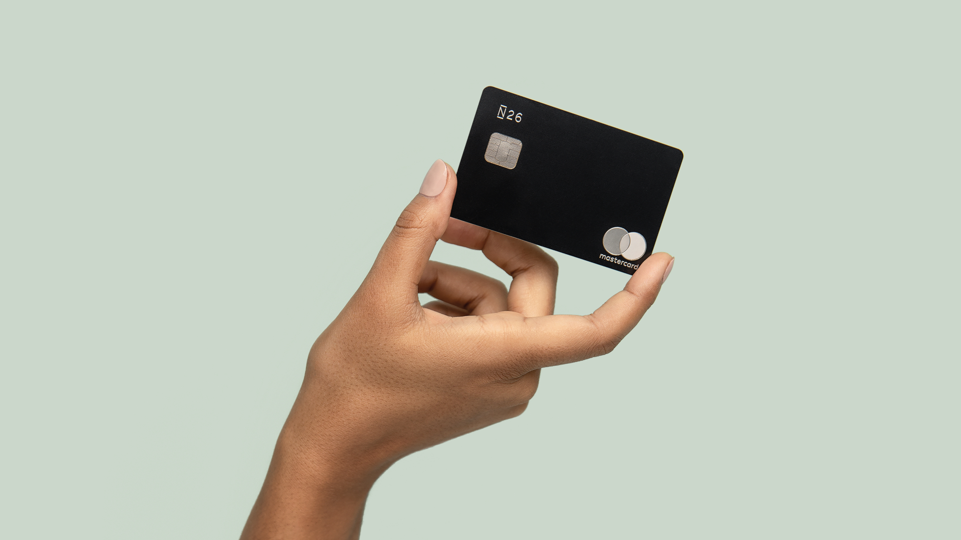 N26 Pressefoto unserer Banking von A–Z Kampagne mit einer Hand, die eine Premium Metal Karte in Carbonschwarz hält