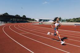 Woman running around track.