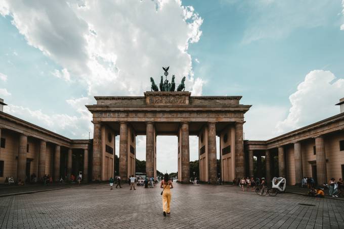 View of Brandenburg Gate with young woman walking towards it.
