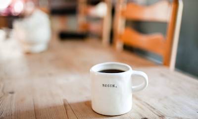 Una taza blanca de café con un logo que dice "BEGIN".