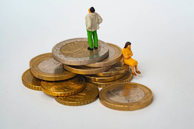 une pile de pièces en euros, un homme debout et une femme assise.