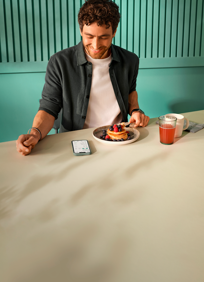 A smiling man looks at her smartphone.