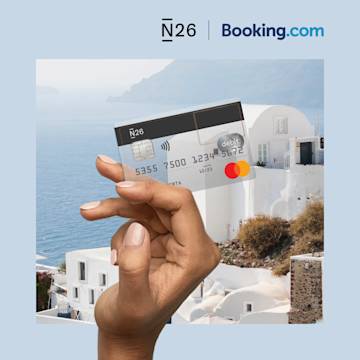 Hand holding a transparent N26 card in front of a Mediterranean vista.