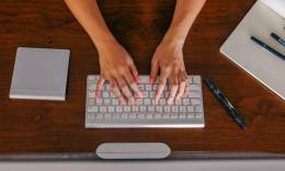 mujer freelance escribiendo en su teclado del escritorio.