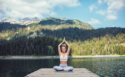 Woman doing yoga on mountain lake.