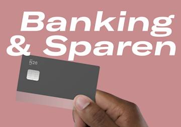 Hand, die eine N26 Debitkarte mit den Worten „Verbringen“ und „Speicher“ im Hintergrund.