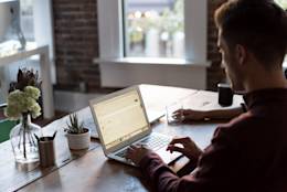Man using a laptop sitting at a table.
