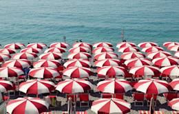 White and red striped parasols on a beach.