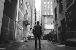 Man stands in an alley next to buildings.