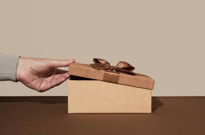 Hand opening brown gift box used as a creative way to give money.