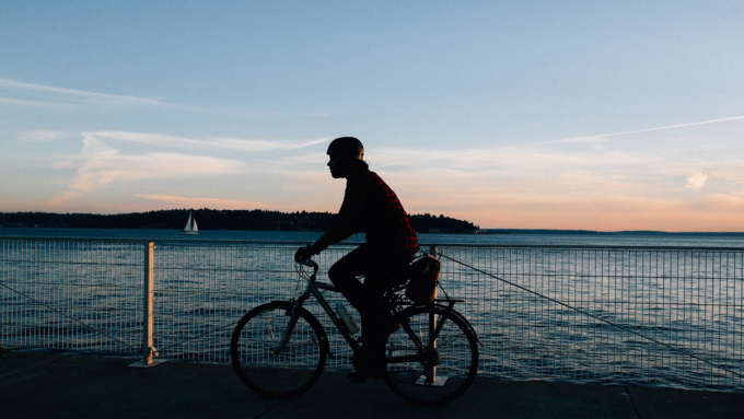 A guy riding a bike in a sunset.