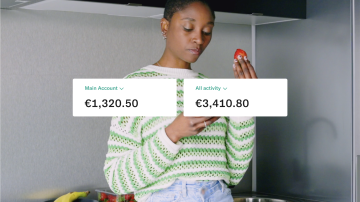 A woman eats a strawberry while checking her bank account activity.