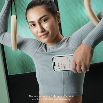 Woman in a gym holding a mobile that is showing the N26 Stocks and ETF feature. In the foreground there is a popup showing the Stocks and ETFs balance.  