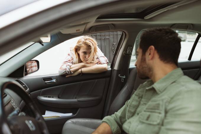 Une femme parle à un homme dans une voiture.