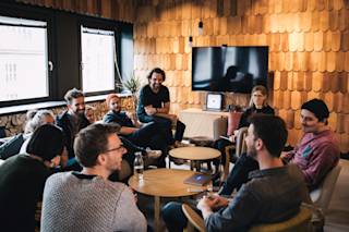 N26 employees sitting on sofas and chairs in a meeting room with wooden walls.