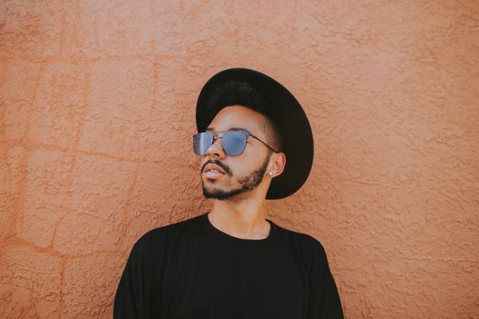 A man with a hat and sunglasses looks off into the distance.